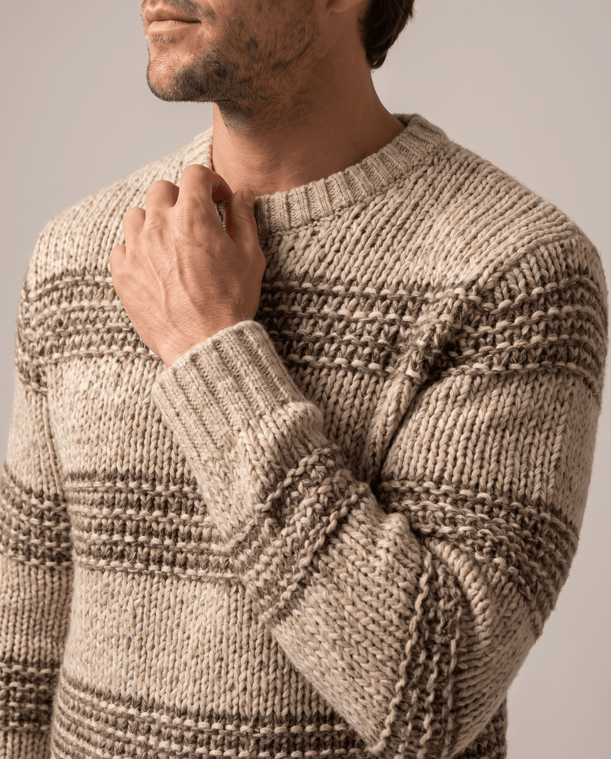 Close-up of hand at the ribbed collar of a khaki striped knit