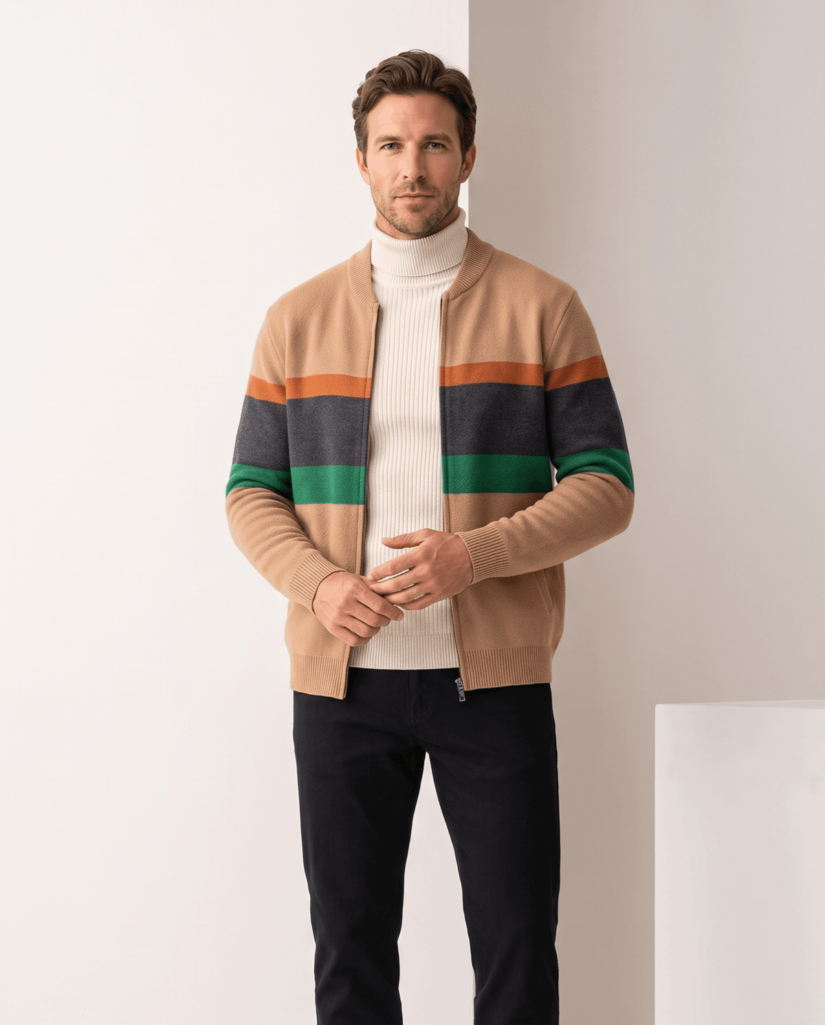 Man wearing a beige zip cardigan with orange, gray and green stripes over a cream turtleneck