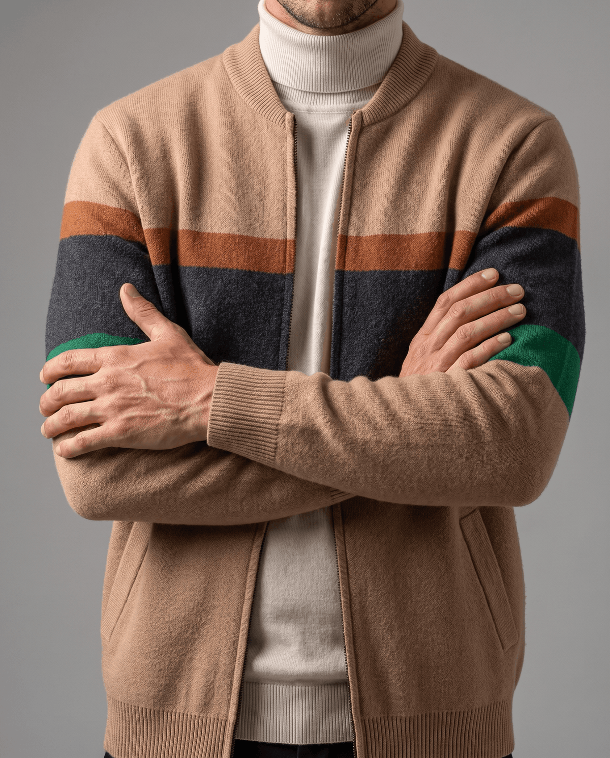 Arms crossed in a beige striped cardigan layered over a white turtleneck sweater