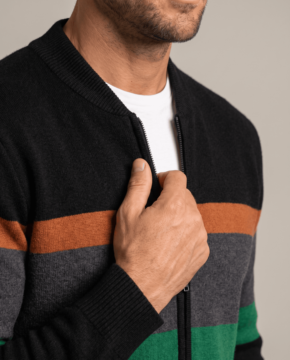 Close-up of hand holding the zip on a black cardigan with a stand collar