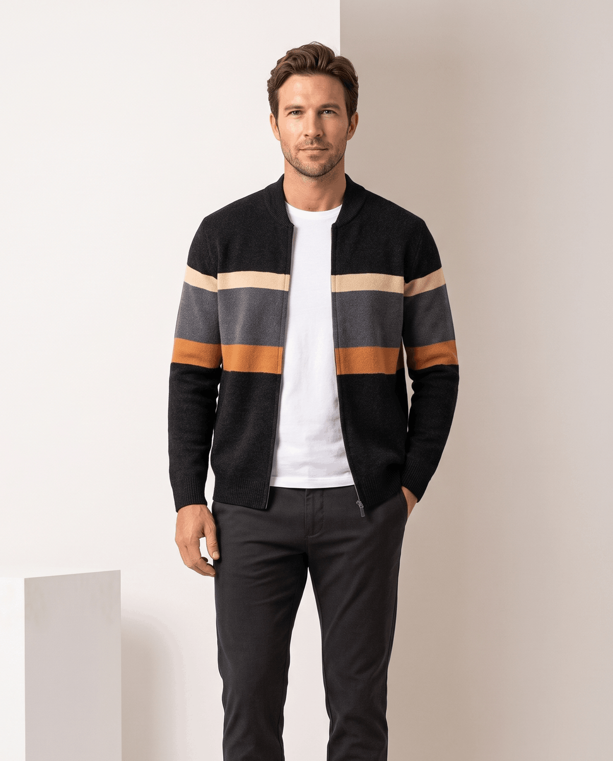 Man in black cardigan with cream, gray and orange stripes worn open over a white tee