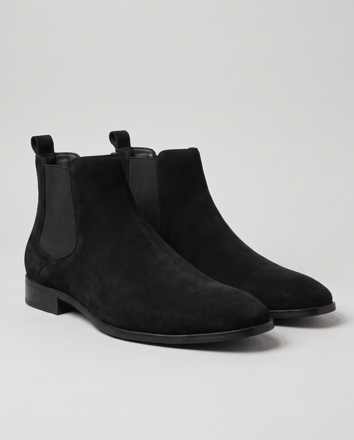 Black suede slip-on boots with pull tabs shown side by side