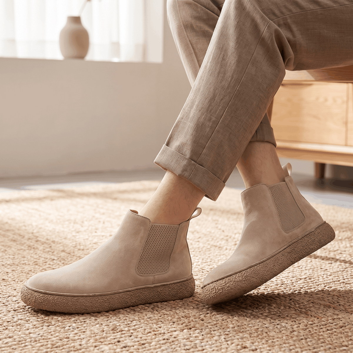 Person wearing beige suede Chelsea boots with light trousers, showing the side profile and textured crepe sole.