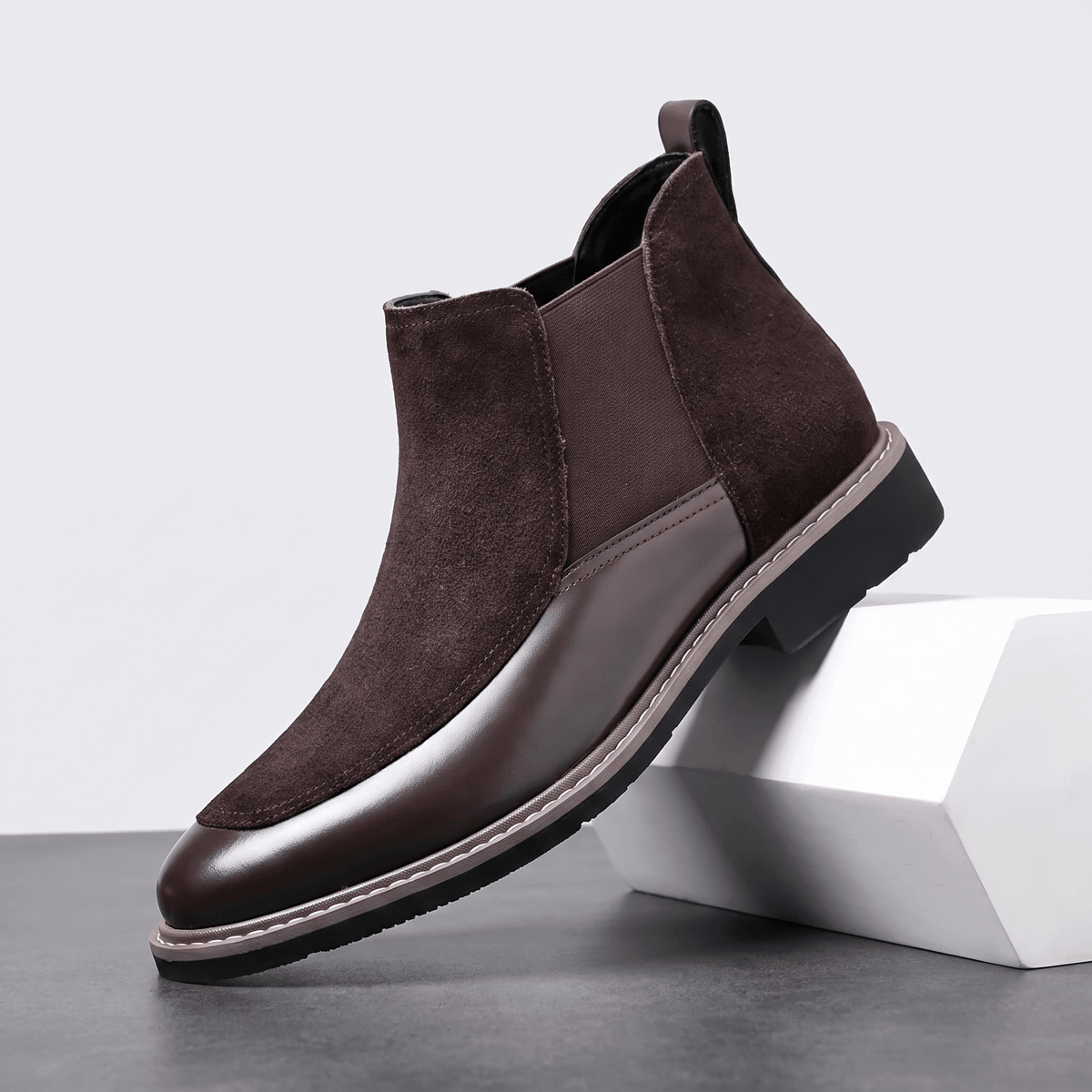 Dark brown suede Chelsea boot with polished leather toe cap, elastic side gore, welt stitching, and a stacked heel.