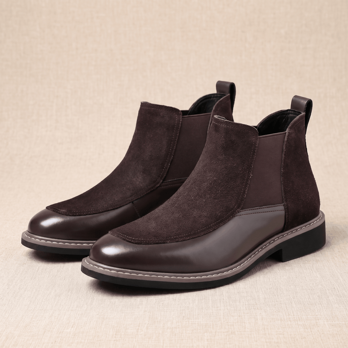 Dark brown suede and polished leather Chelsea boots with elastic side gores, welt stitching, and a stacked heel.