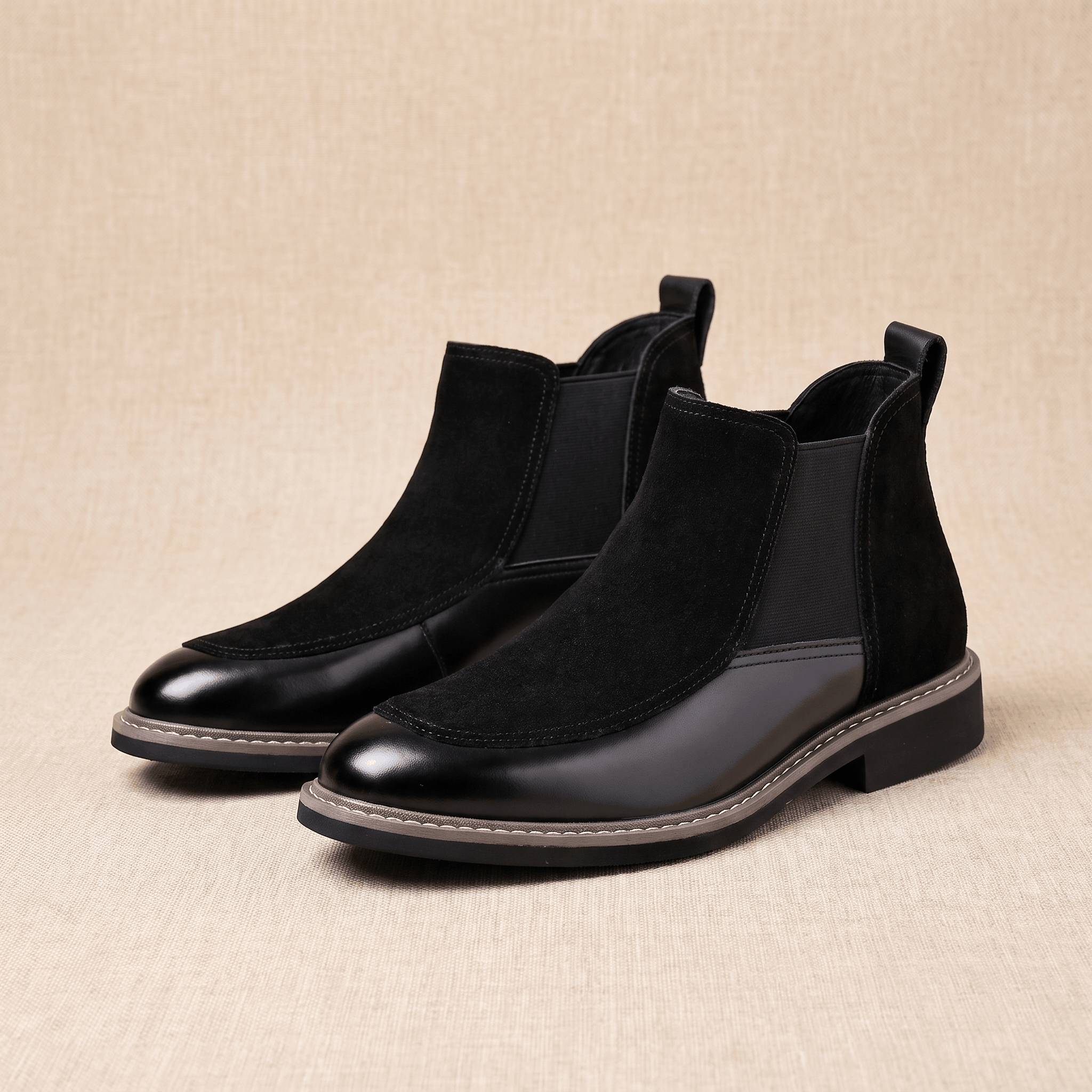 Black suede and polished leather Chelsea boots featuring an almond toe, elastic side gores, and a welt-stitched stacked heel.