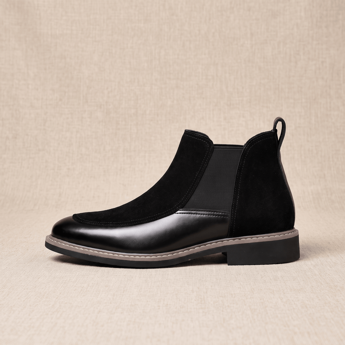 Black suede Chelsea boot with polished leather toe cap, elastic side gore, welt stitching, and a low stacked heel.