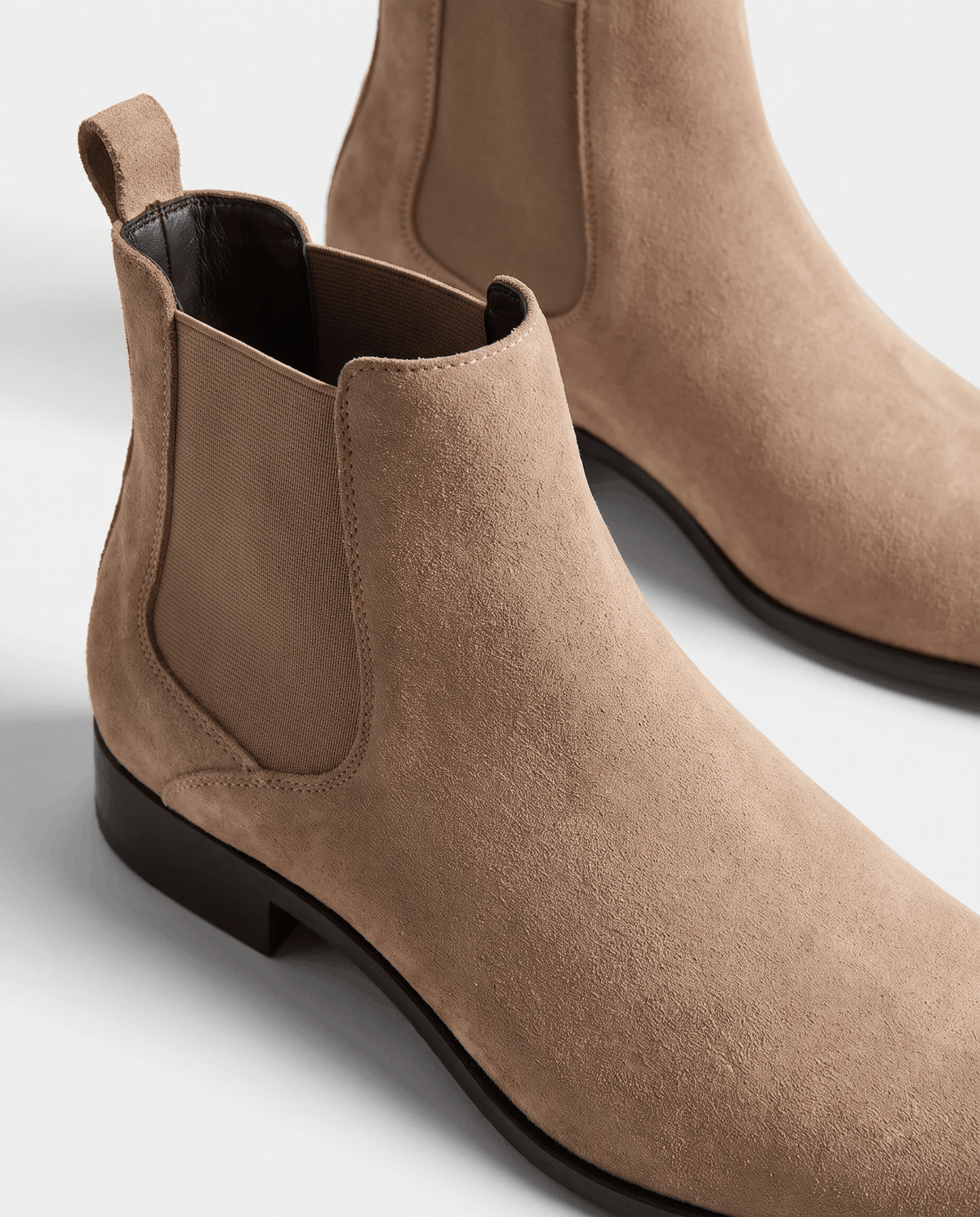 Close-up of taupe suede texture and dark elastic panel on a Chelsea boot