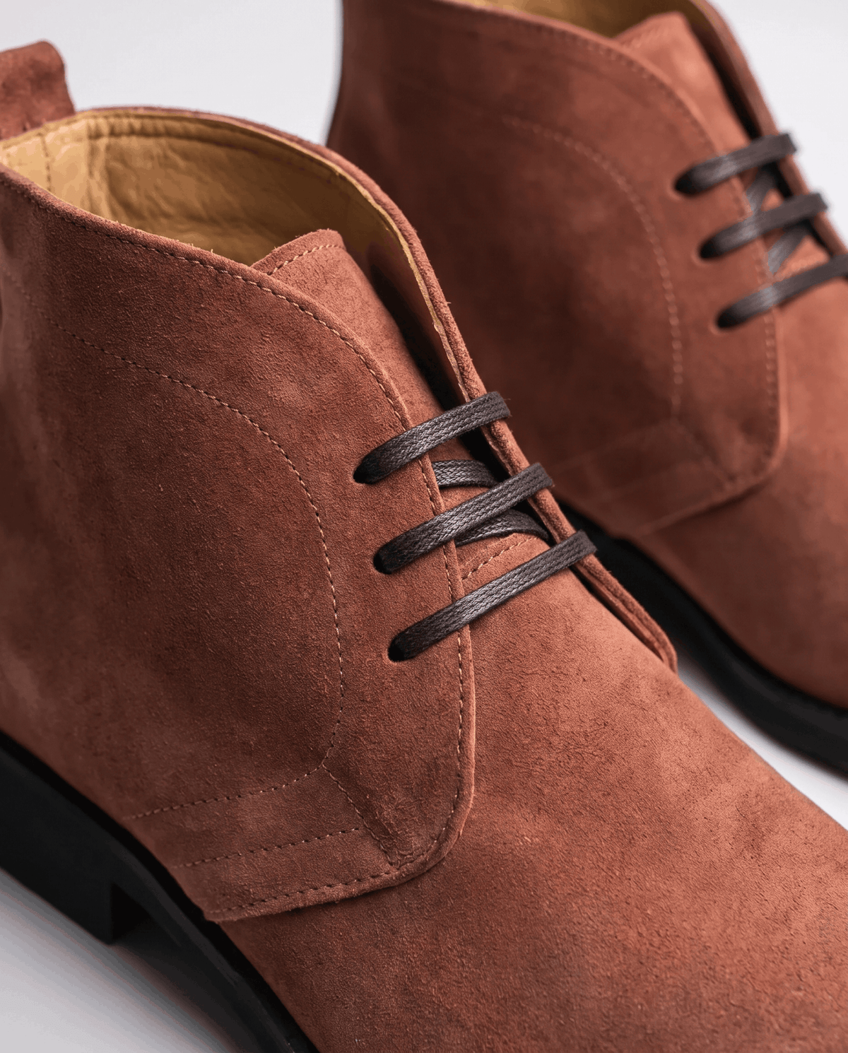 Close-up of brown suede chukka boot showing the short lace-up and cushioned lining.