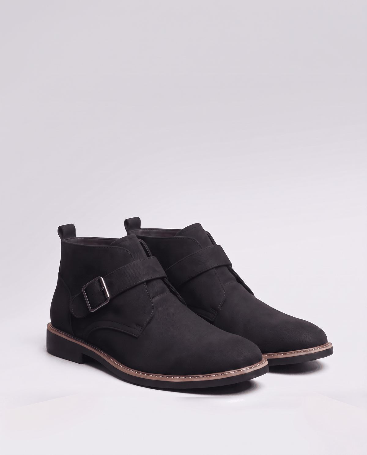 Pair of black suede boots with buckle straps on a soft grey studio background