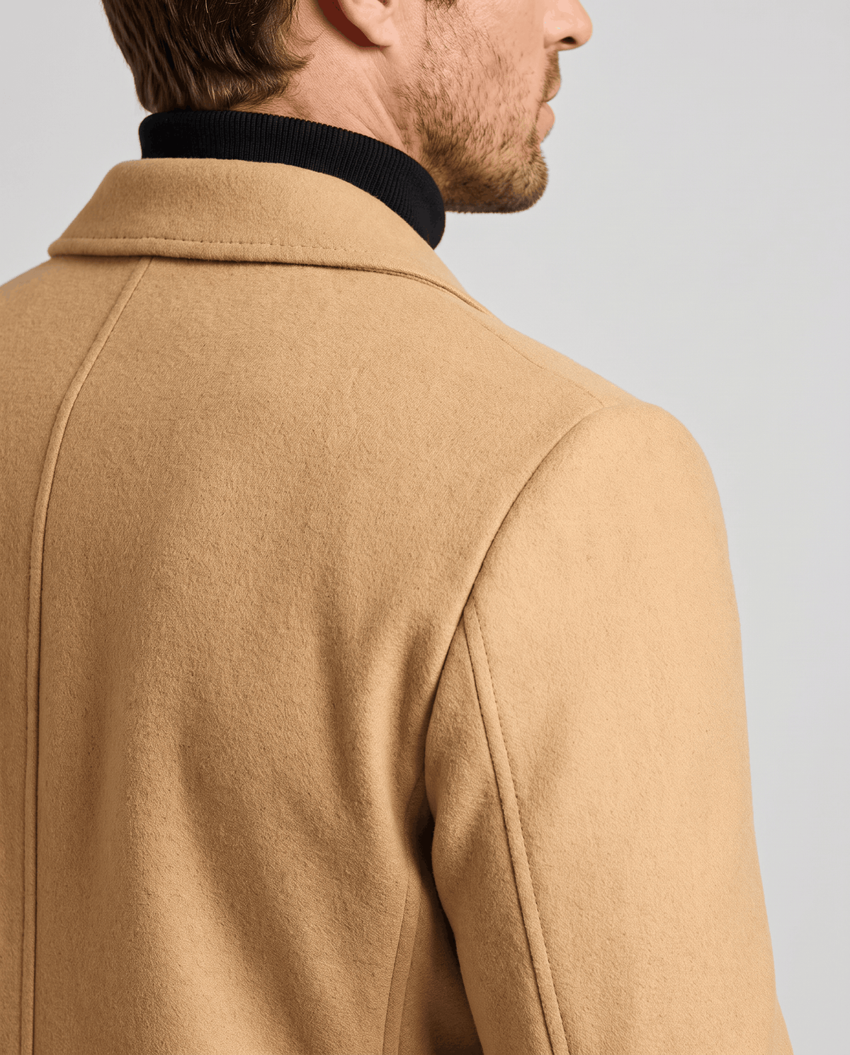 Close-up of the khaki overcoat's smooth fabric at the collar and shoulder seam