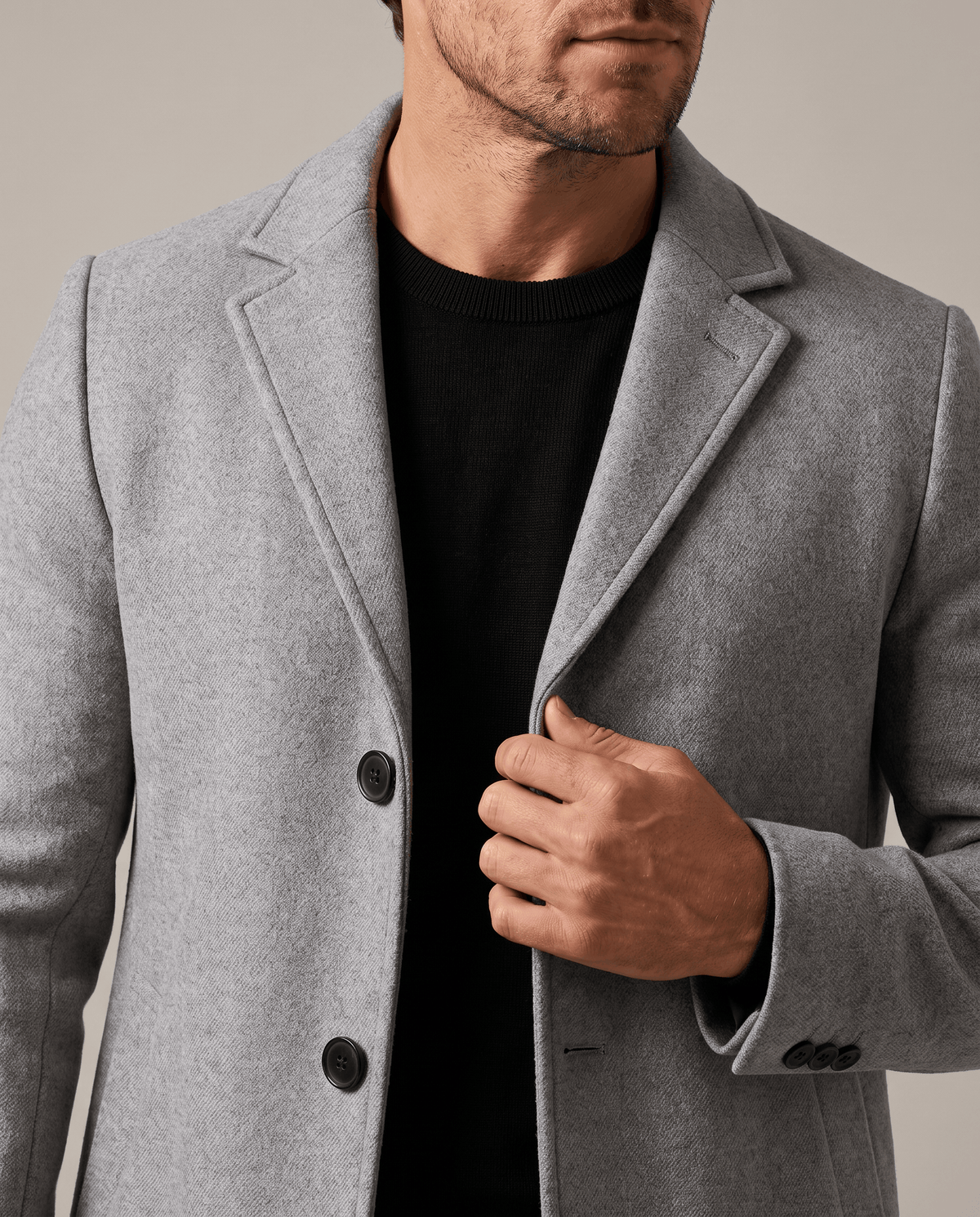 Light gray overcoat lapel and collar detail, worn over a black top