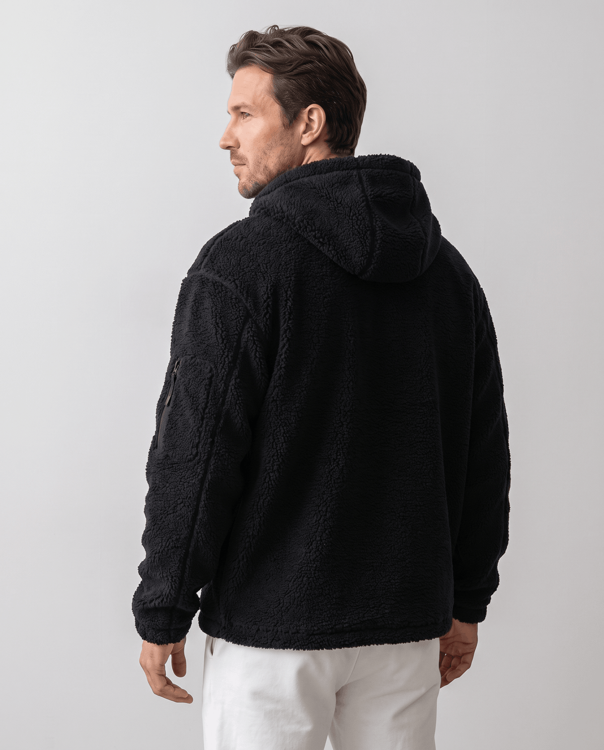 Back view of black hooded jacket paired with white pants