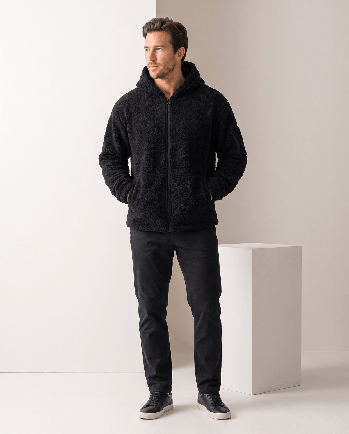Full-length black outfit with dark trousers and sneakers in studio