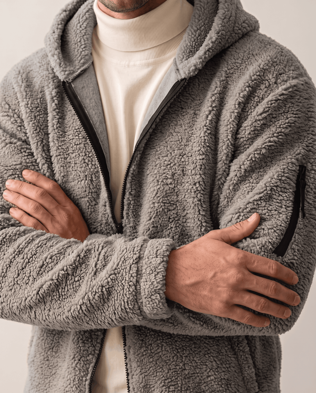 Arms crossed over cream turtleneck showing gray sleeve zip pocket