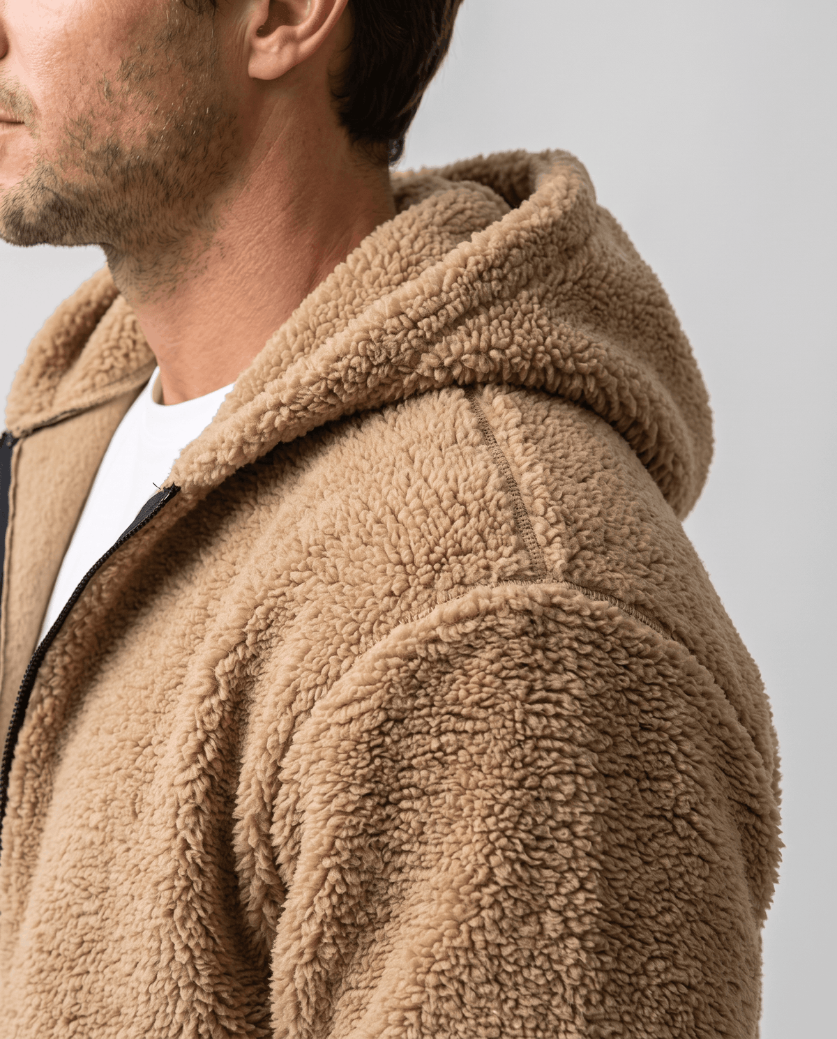 Close-up of khaki hood and shoulder layered over a white tee