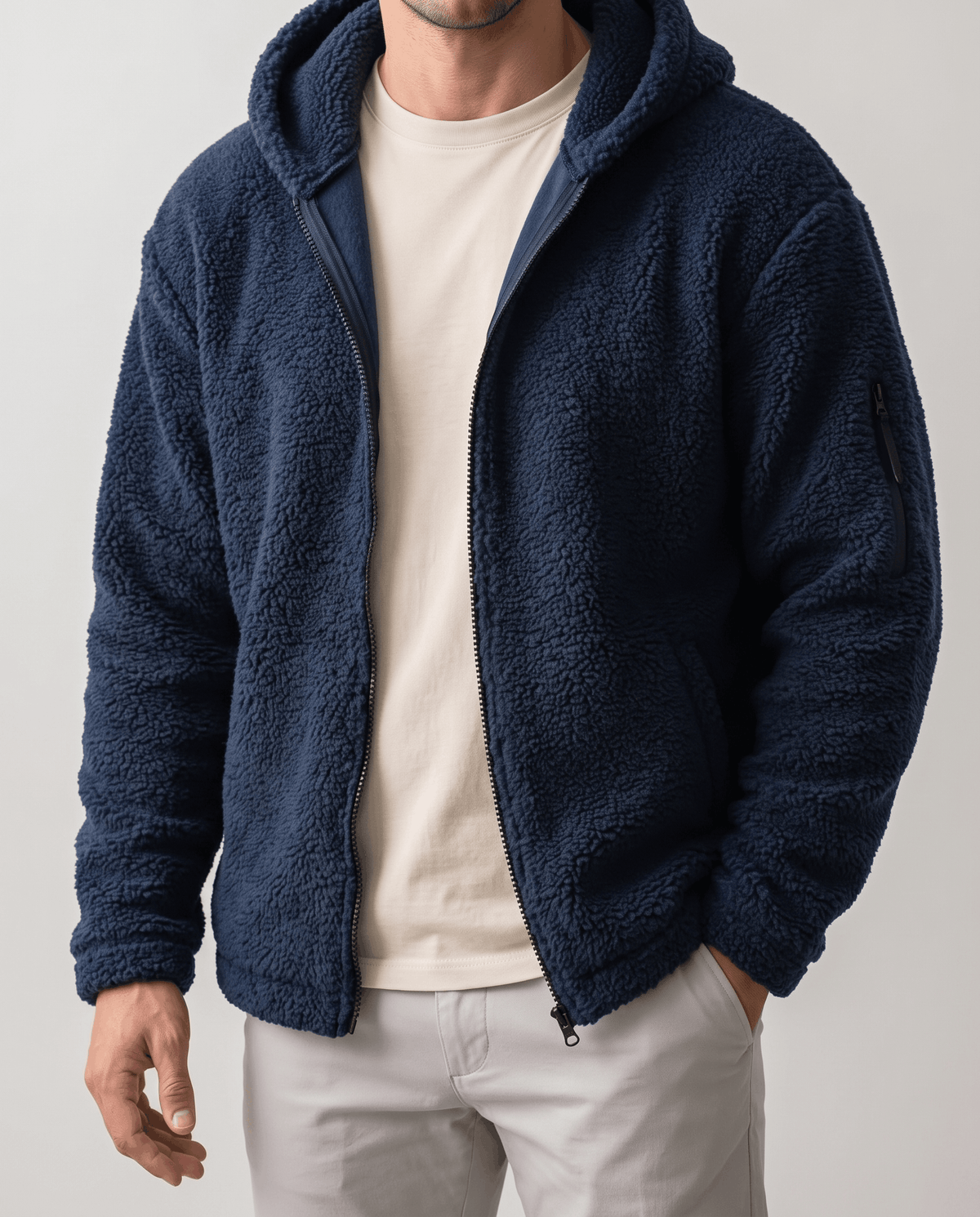 Open navy full-zip jacket worn over a cream tee and stone pants