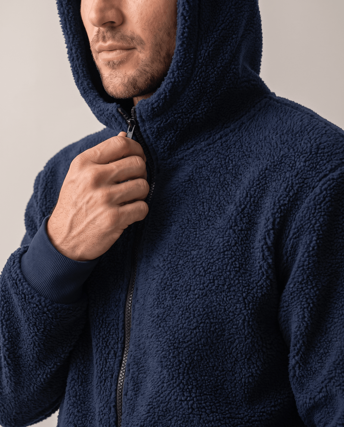 Hand pulling up the navy front zipper with hood raised