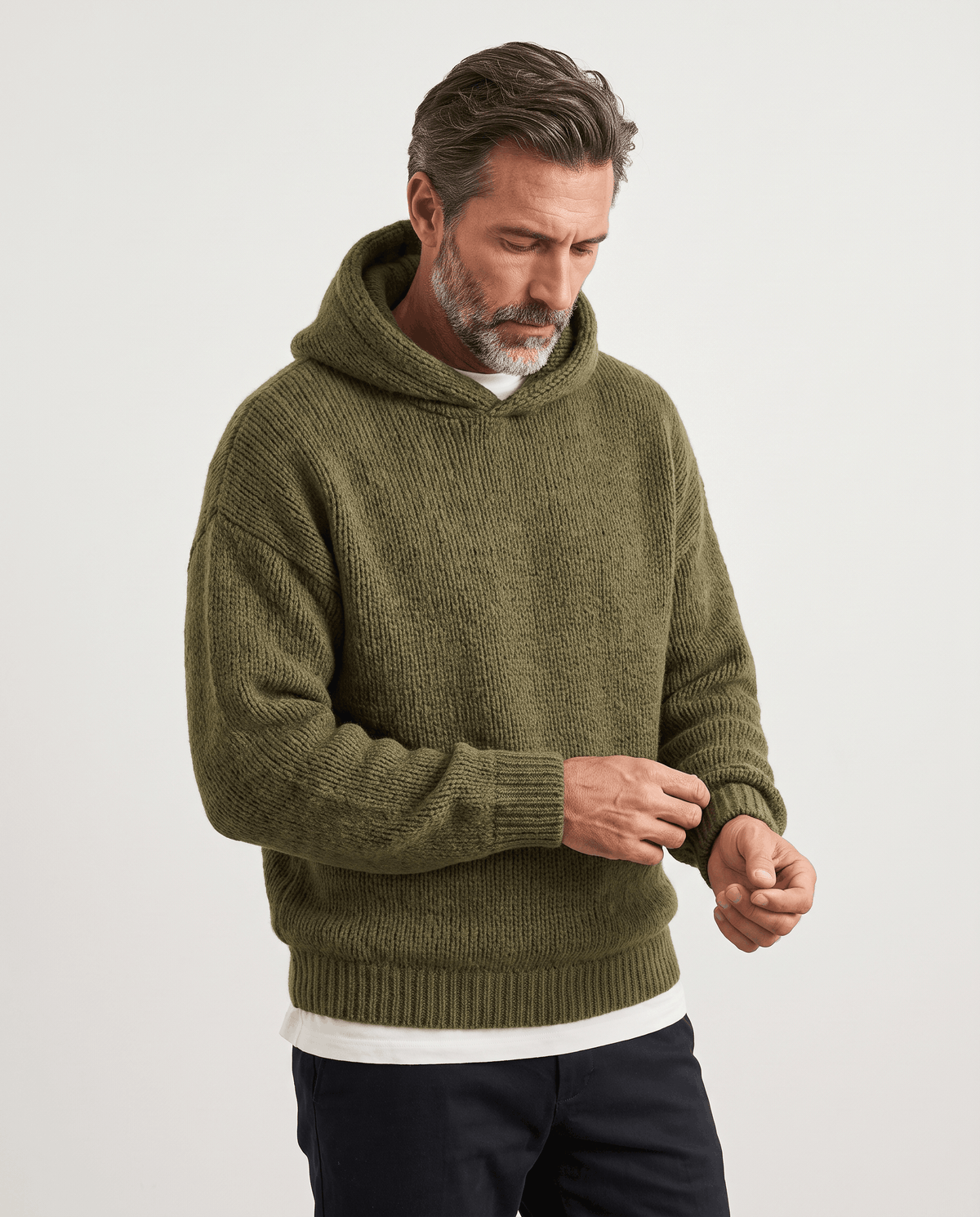 Green knit pullover with a hood, man adjusting the ribbed cuff, front view
