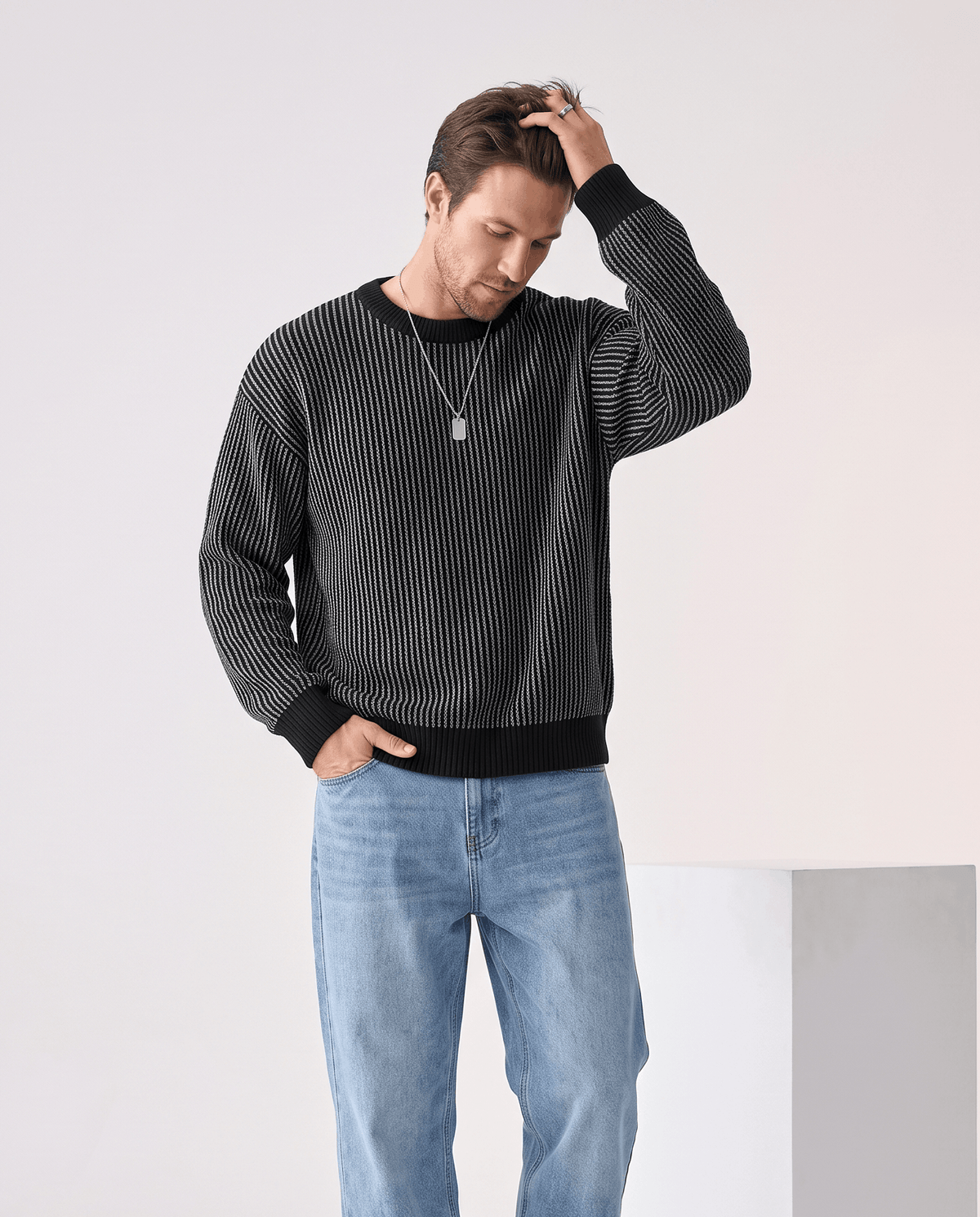 Man wearing men's two-tone ribbed knit crew neck sweater in black with light jeans