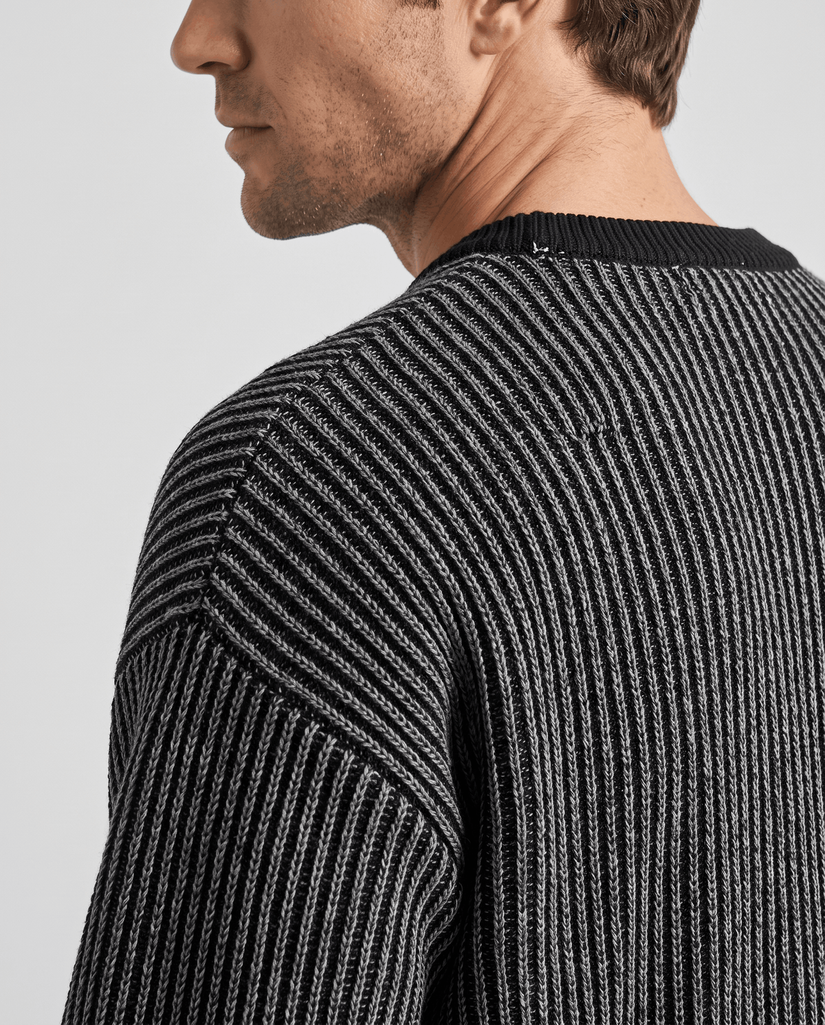 Side close-up of black striped sweater showing dropped shoulder seam