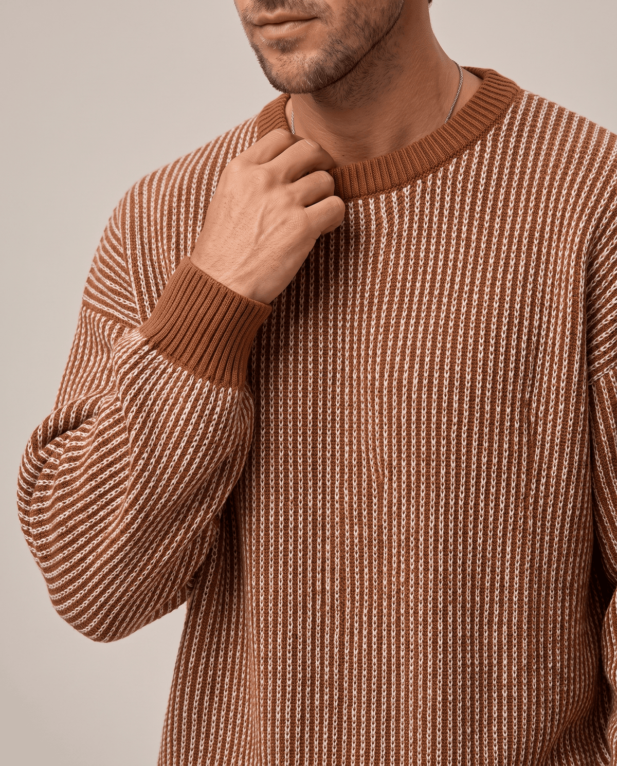 Close-up of hand at the rust ribbed collar of a brown striped knit