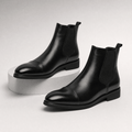 Black vegan leather cap toe Chelsea boots with elastic side gussets, rear pull tabs, and a treaded rubber outsole.