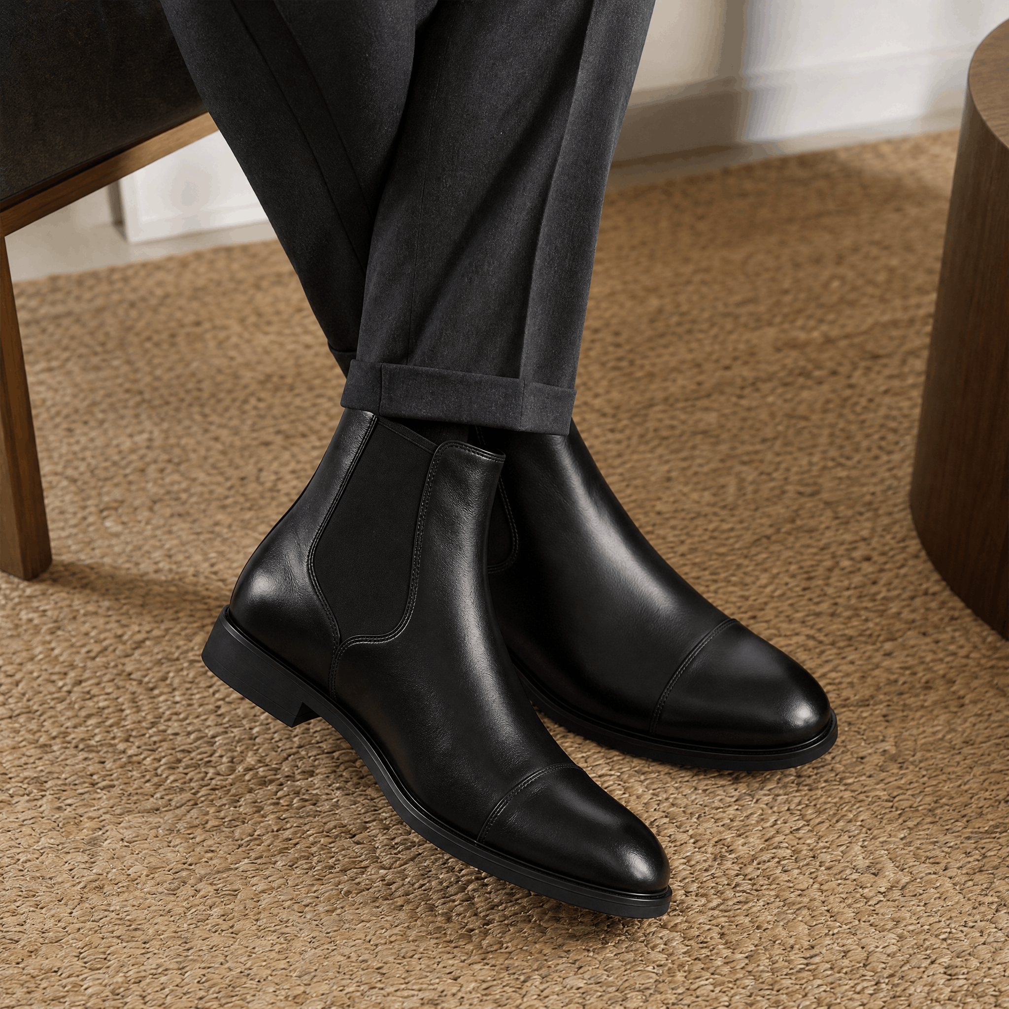 Black vegan leather cap toe Chelsea boots with elastic side gussets, worn with tailored trousers.