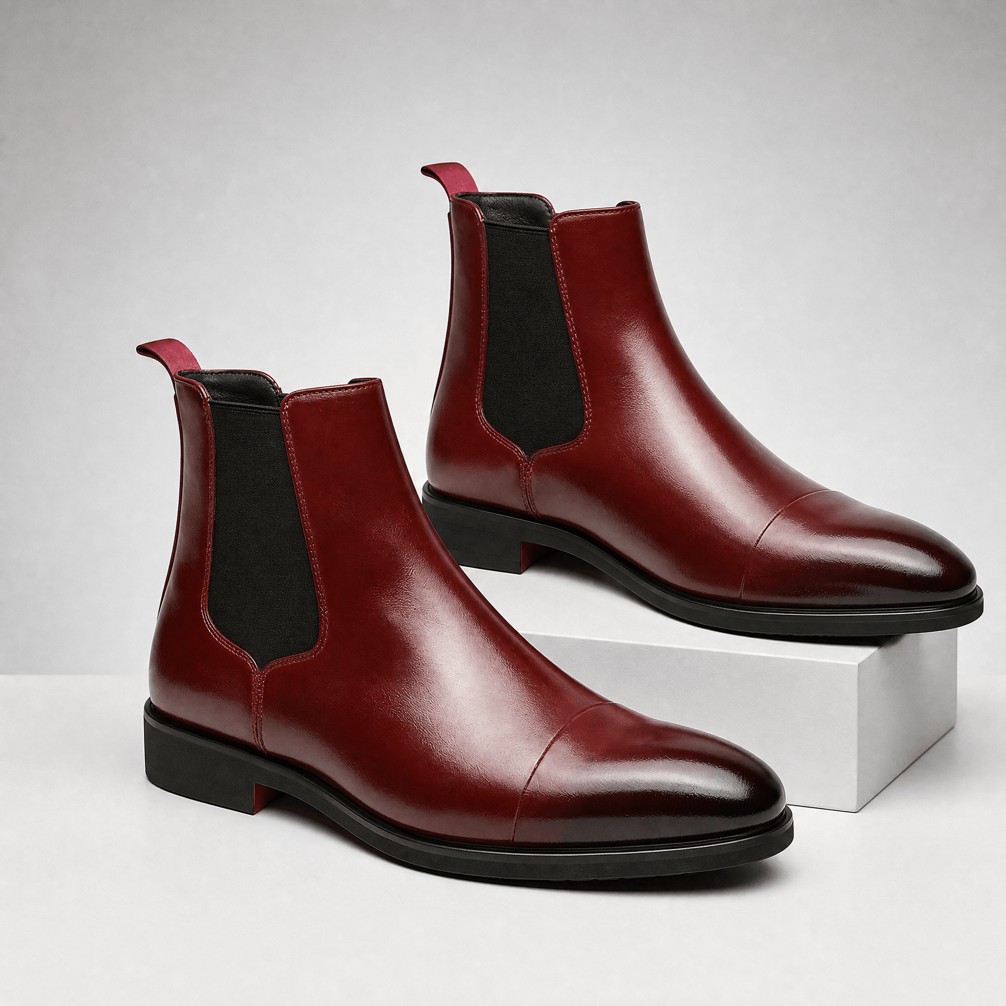 Burgundy vegan leather Chelsea boots with cap toe detailing, black elastic side gussets and a rubber outsole.