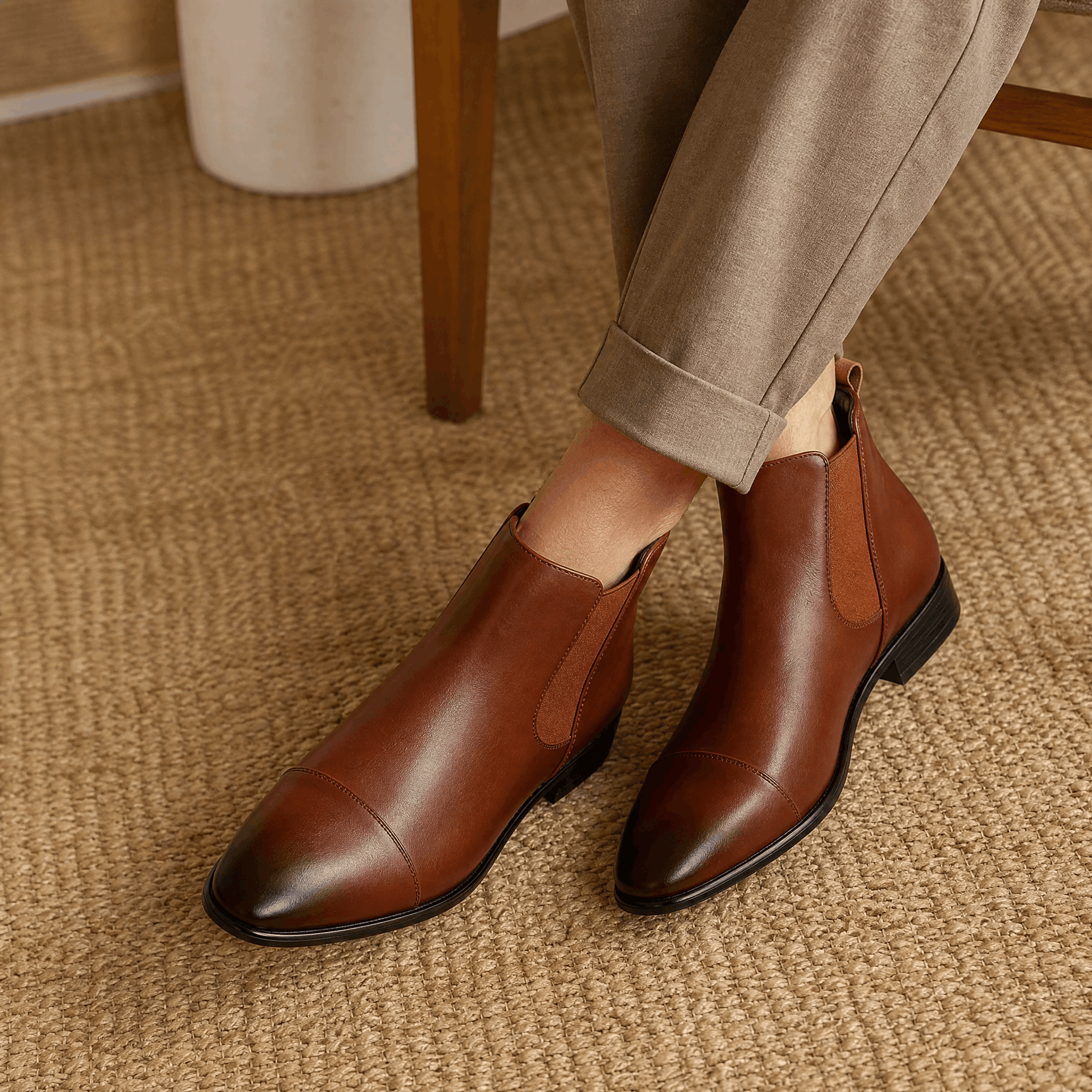 Brown vegan leather cap toe Chelsea boots with a low rubber heel, worn with tailored trousers.