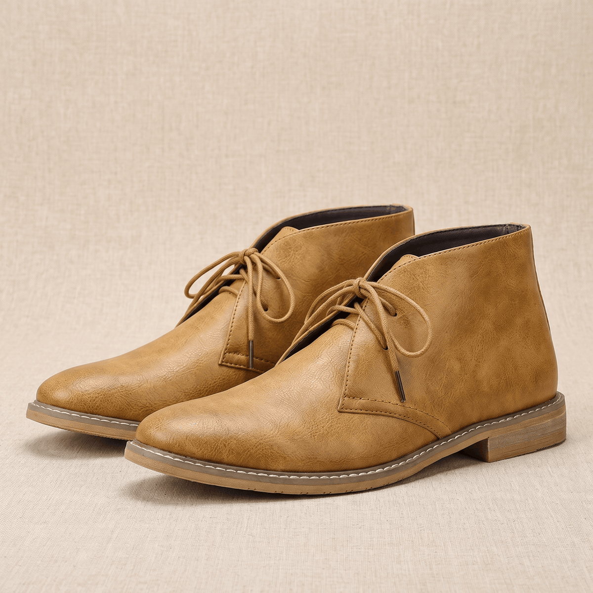 Pair of light brown vegan leather chukka boots with three-eyelet lacing and lug soles.