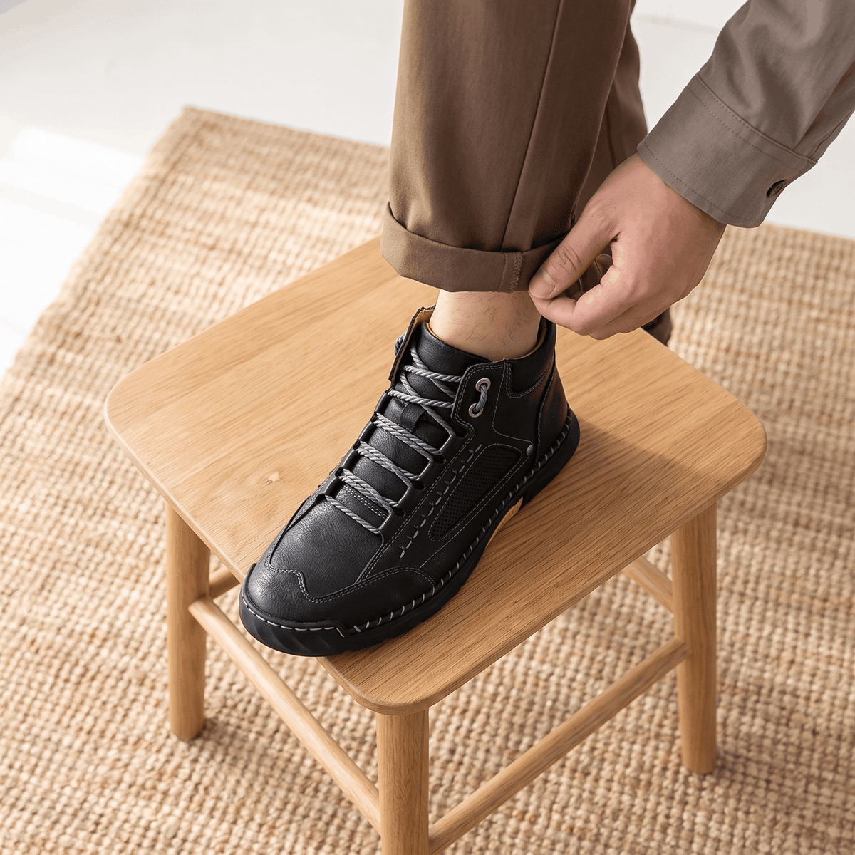 Black vegan leather hiking boot with a wide toe box, mesh side panels, and a thick lug outsole resting on a wooden stool.