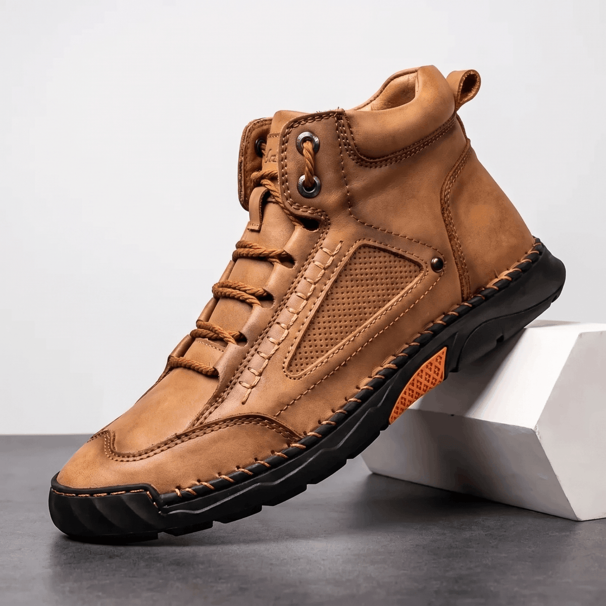 Tan vegan leather hiking boot with a wide toe box, mesh side panel, and a durable black lug outsole on a white block.