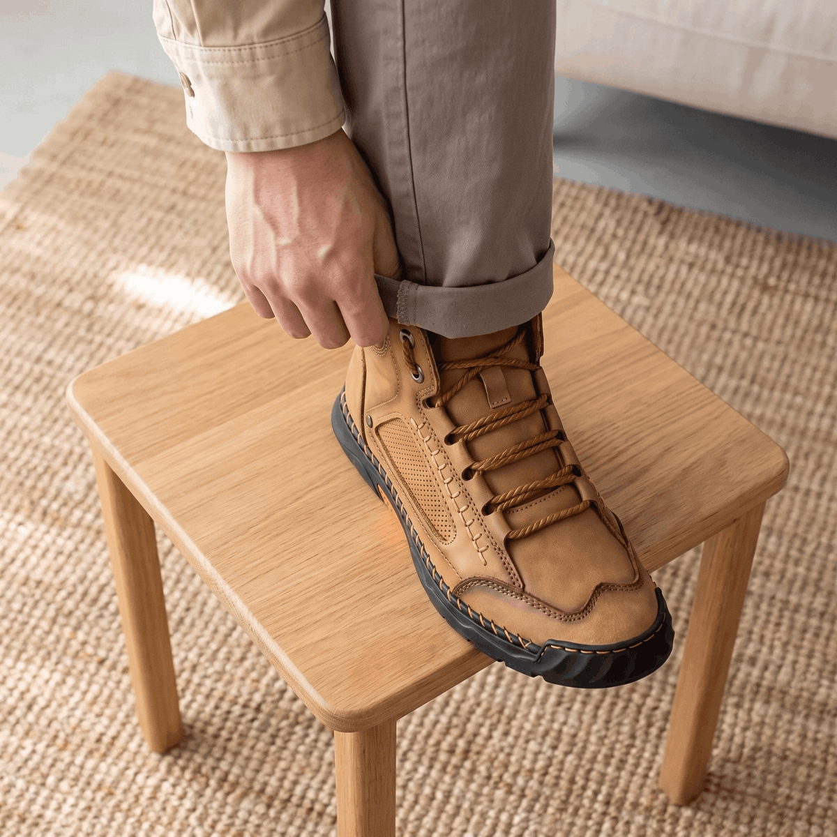 Tan vegan leather hiking boot with a wide toe box, lace-up closure, and black lugged rubber sole resting on a wooden stool.