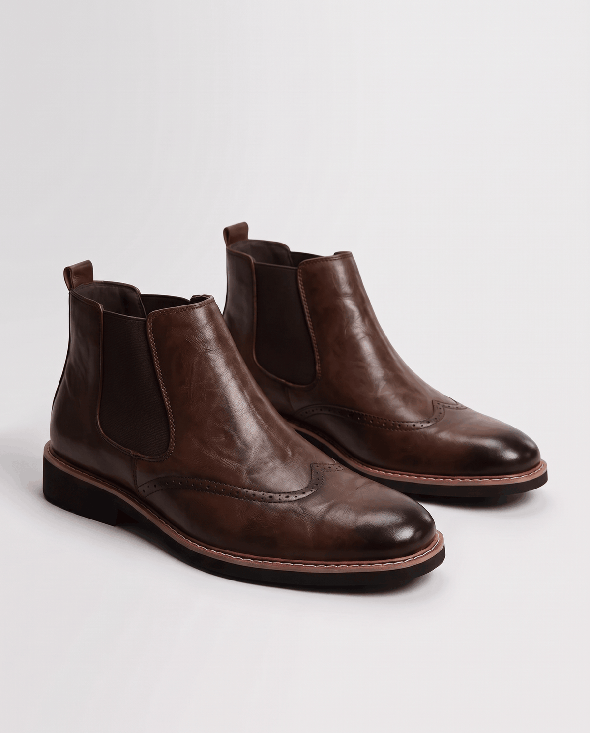 Men's wingtip Chelsea boots in brown vegan leather, shown as a pair on a studio backdrop