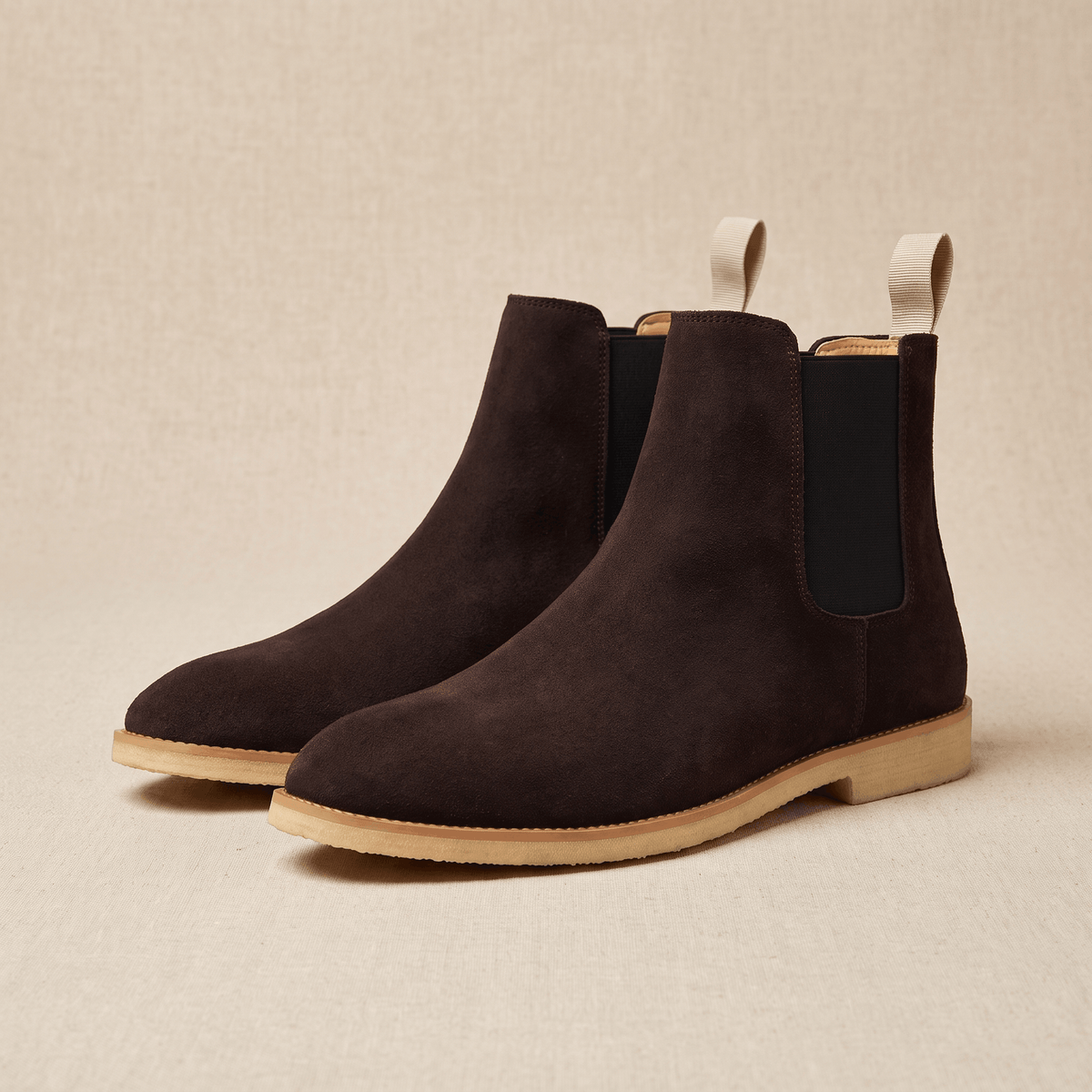 Pair of dark brown vegan suede Chelsea boots with elastic side panels, pull tabs, and light-coloured soles.