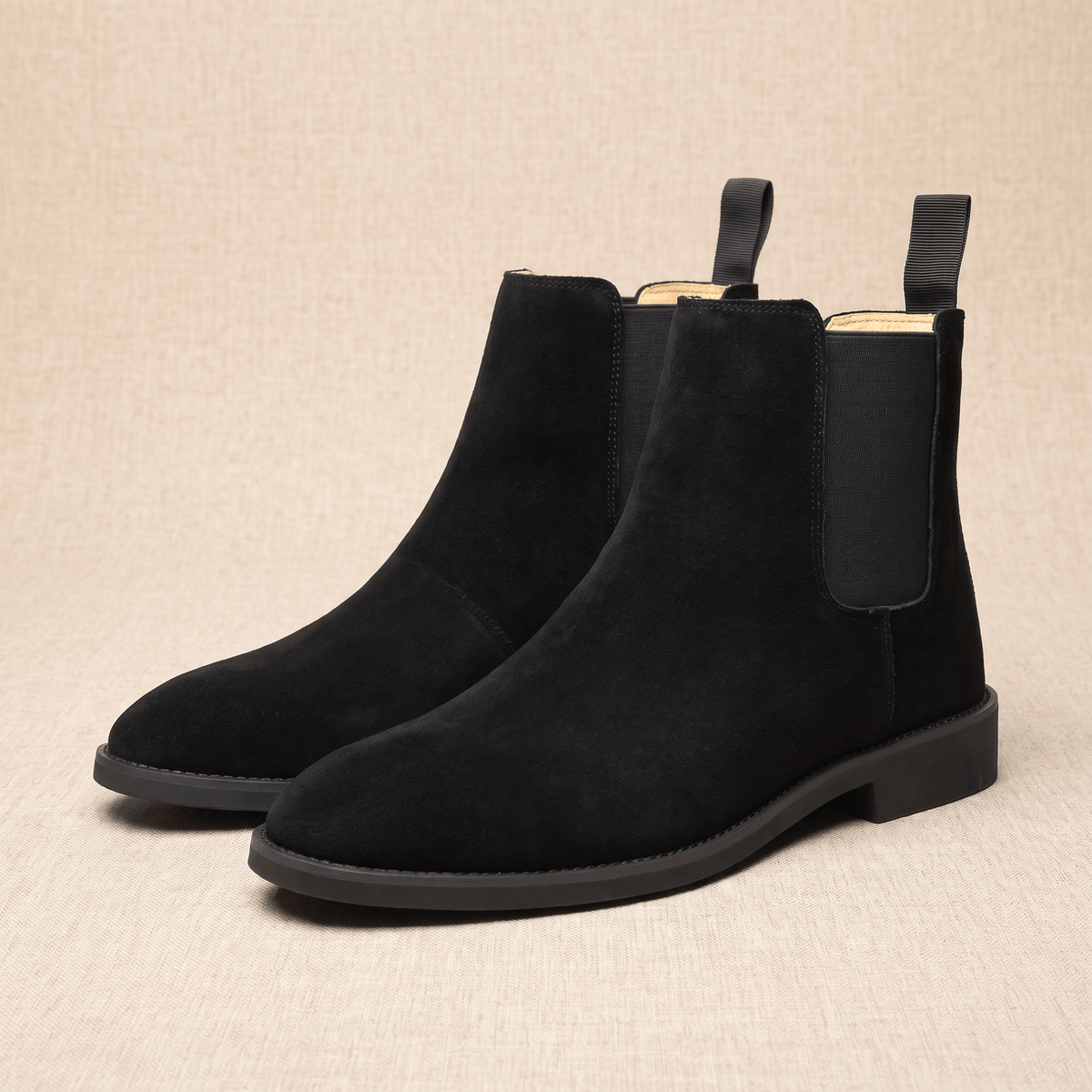 Pair of black vegan suede Chelsea boots featuring elastic side panels, pull tabs, and low-profile soles.
