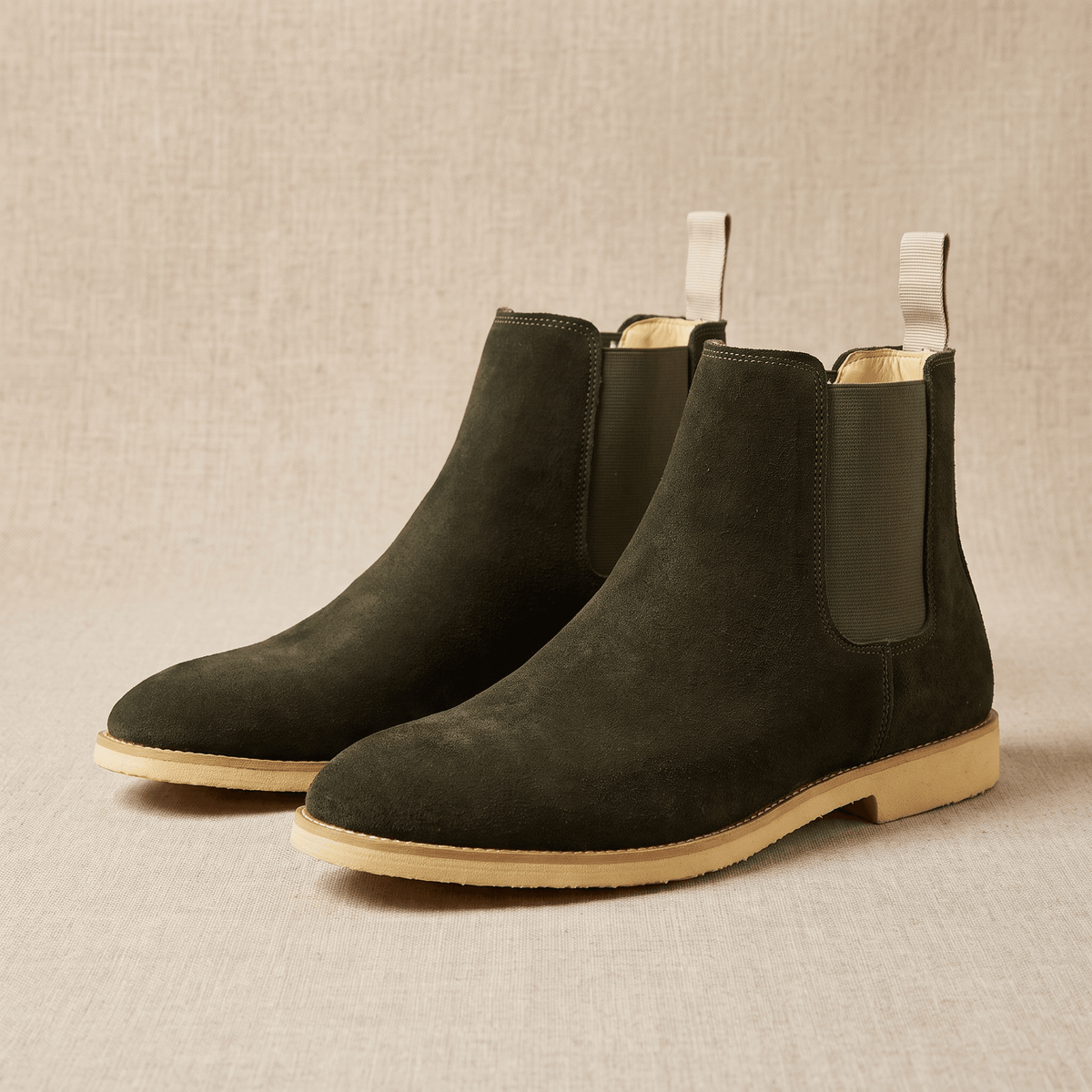 Pair of dark green vegan suede Chelsea boots on a neutral background.