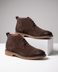 Dark brown vegan suede chukka boots with three-eyelet lacing, stitched welt detail, and a flat rubber outsole.