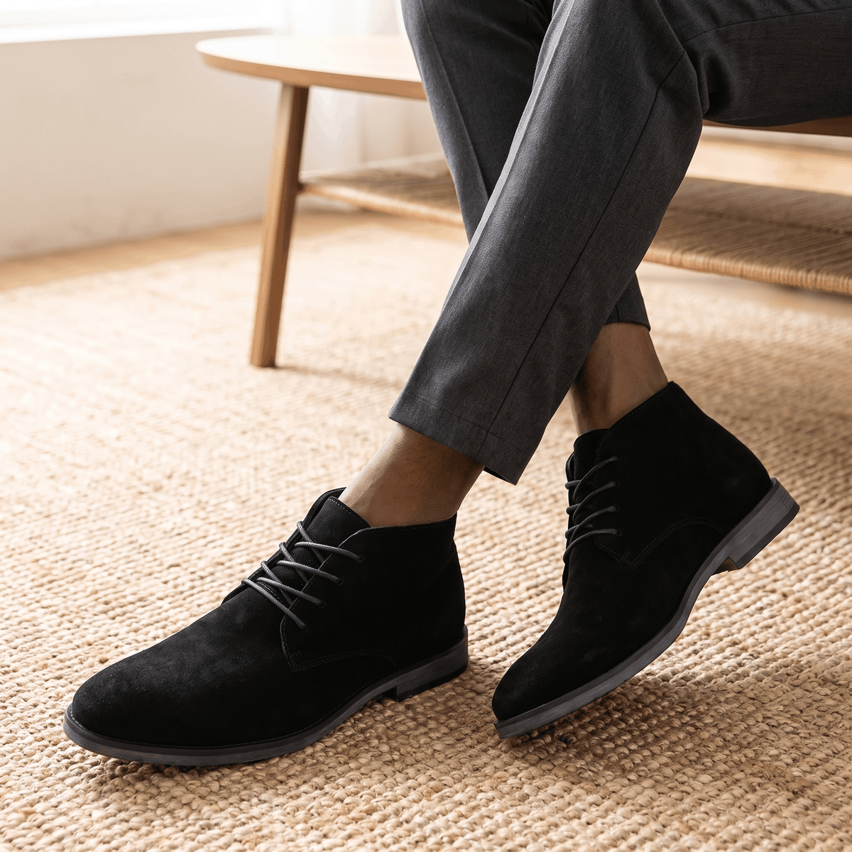 Black vegan suede desert boots with slim stitched soles worn with dark trousers indoors.