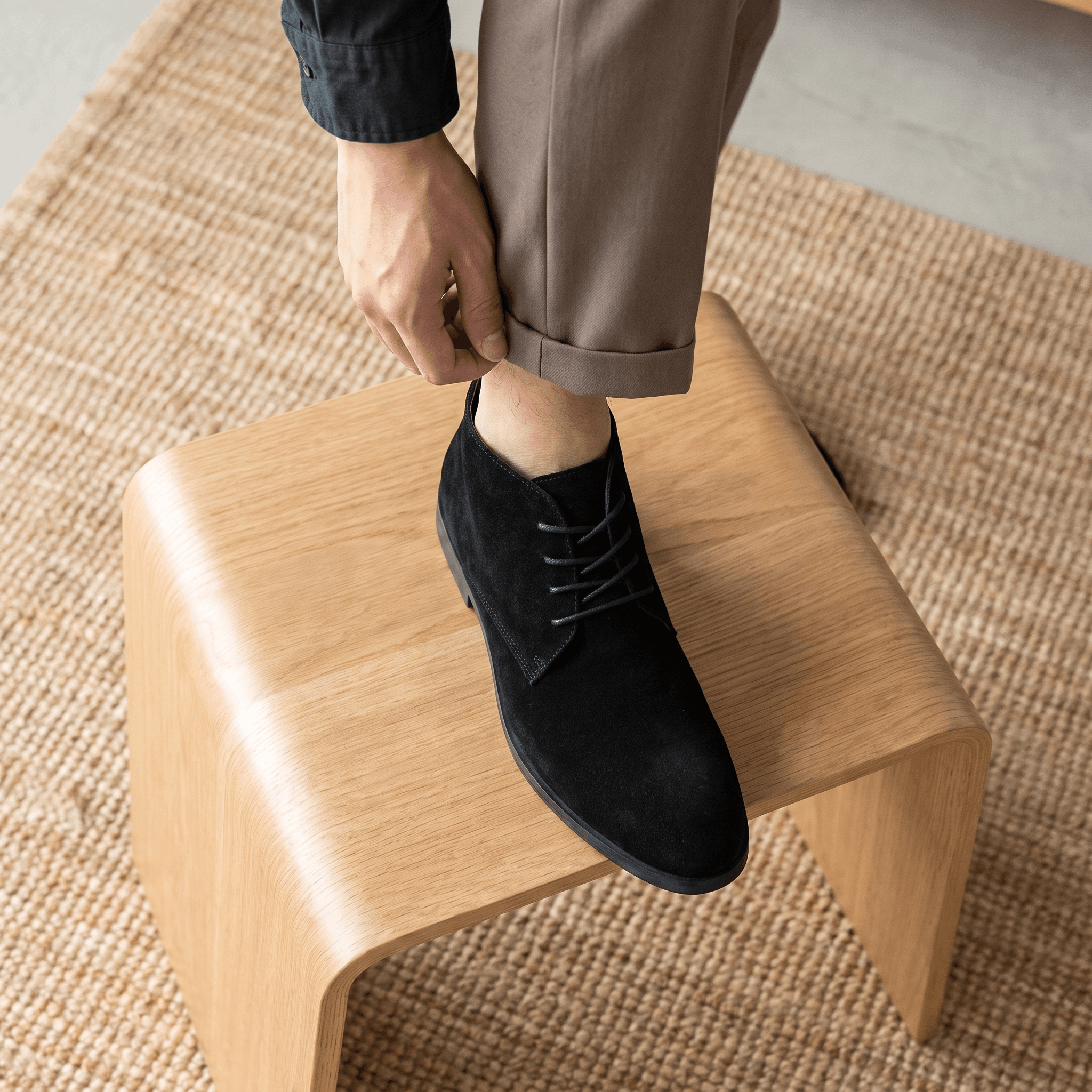 Black vegan suede desert boot being put on while seated.