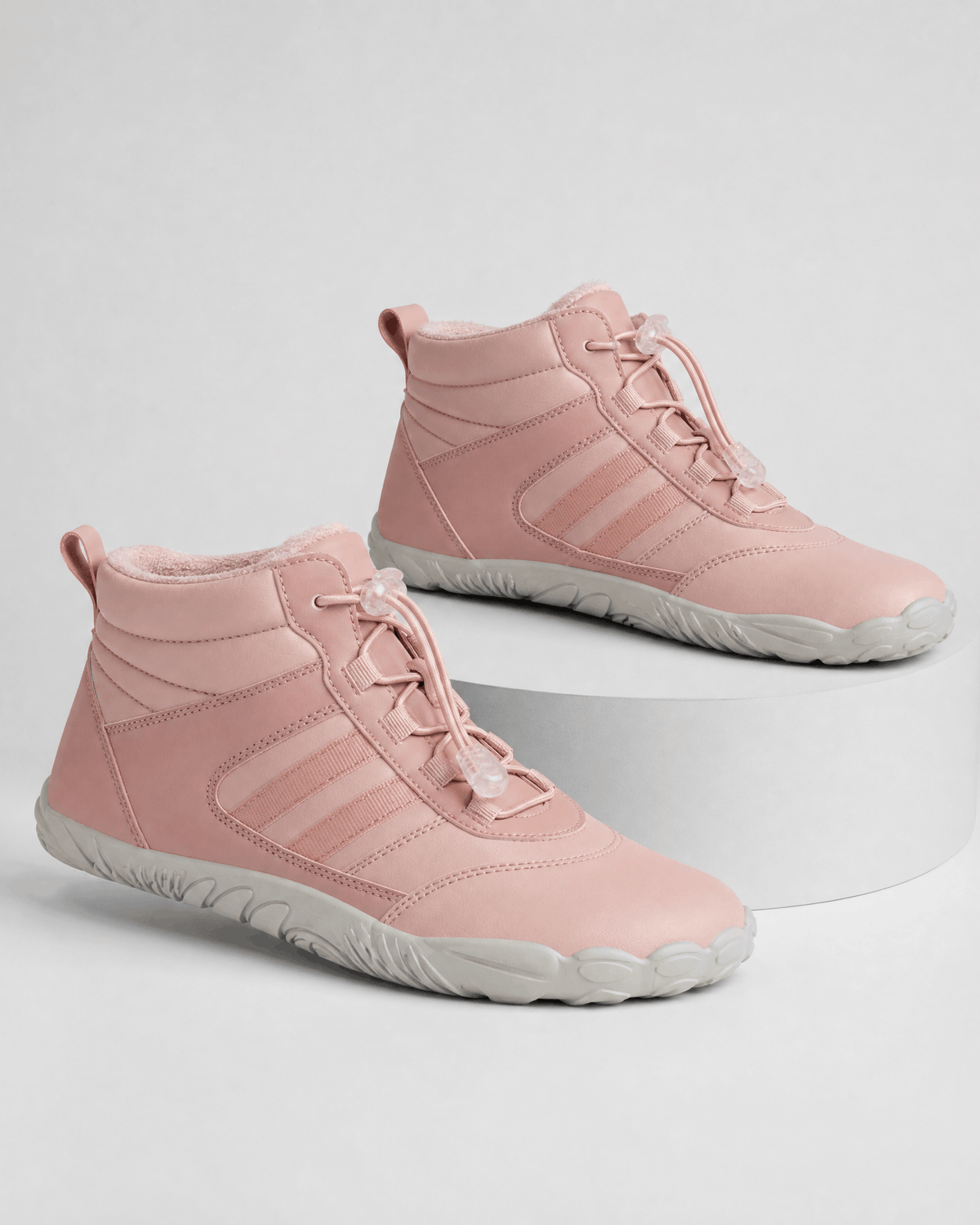 Pink water-repellent winter ankle boots with fleece-lined collars, bungee lace toggles, and flexible grey rubber soles.