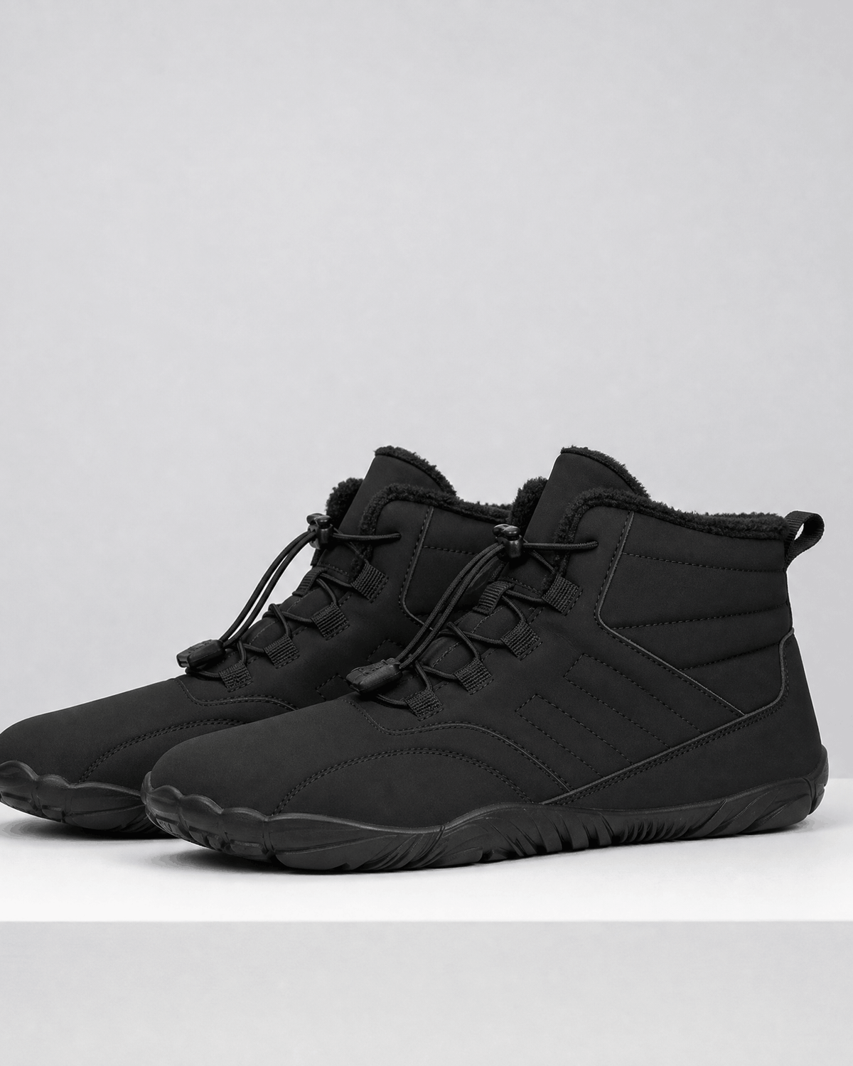 Black water-repellent winter ankle boots with a fleece-lined collar, flexible rubber sole, and bungee lace toggle system.