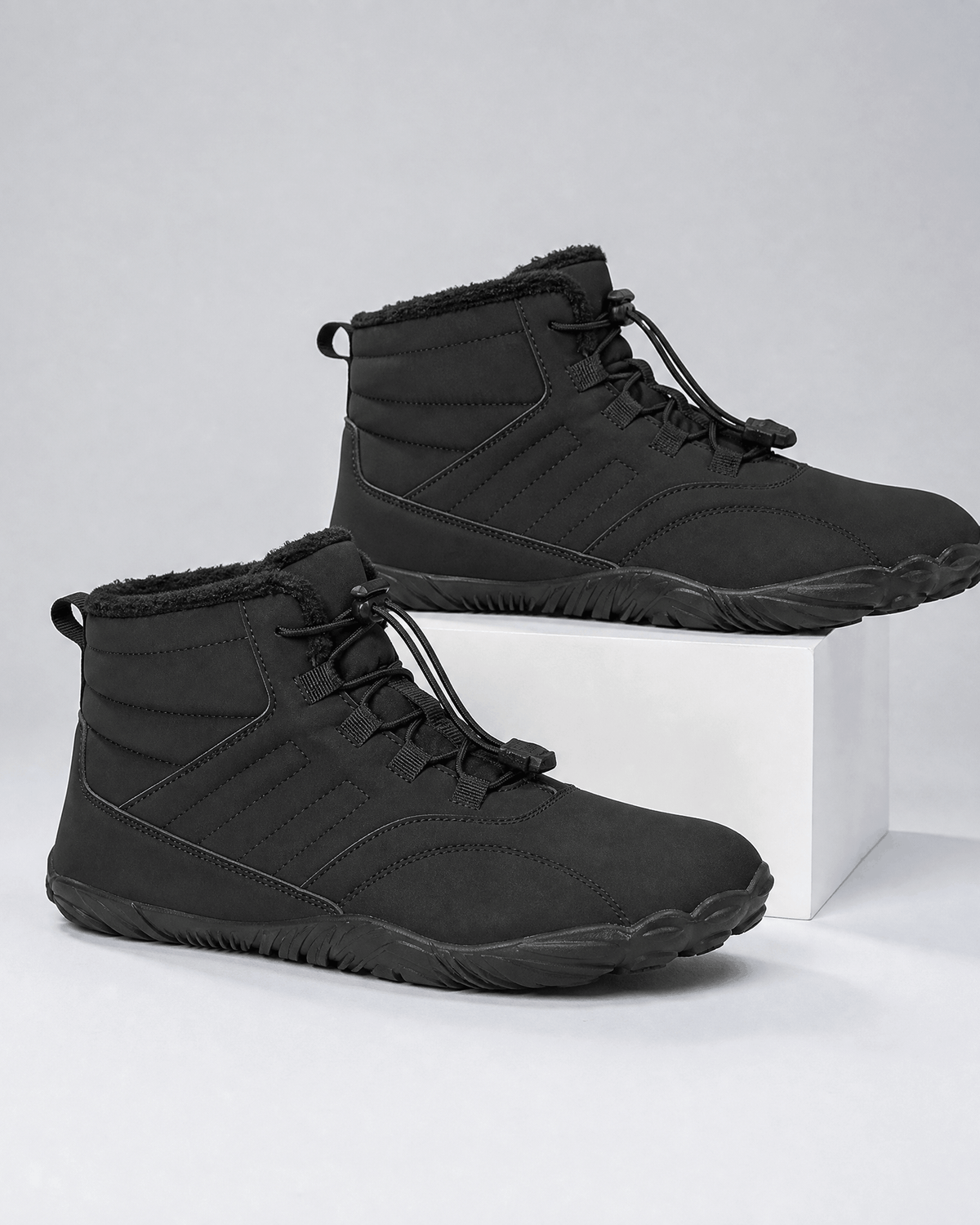 Black water-repellent winter ankle boots with fleece-lined collars, bungee lace toggles, and flexible rubber soles.