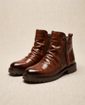 Brown waxed leather boots with a ruched shaft, side zip closure, and a sturdy, slip-resistant lug sole.