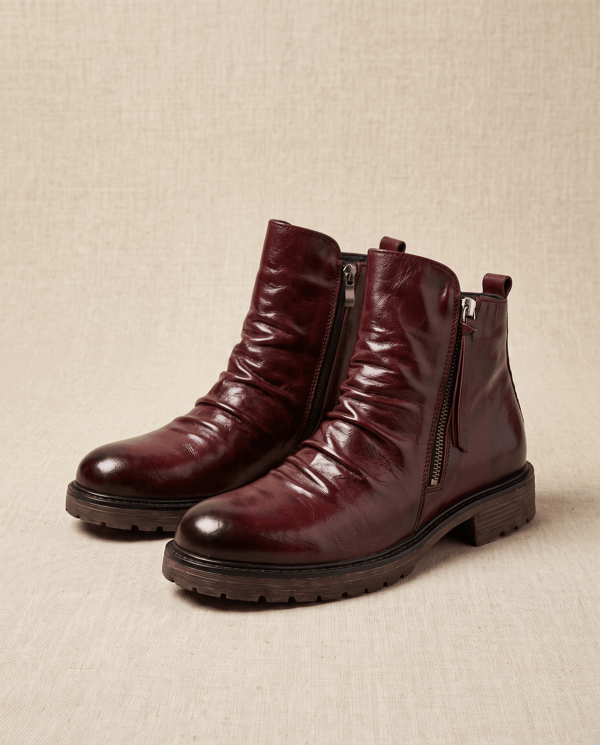 Deep red waxed leather boots with a ruched ankle, side zip closure, and a sturdy, slip-resistant lug sole.
