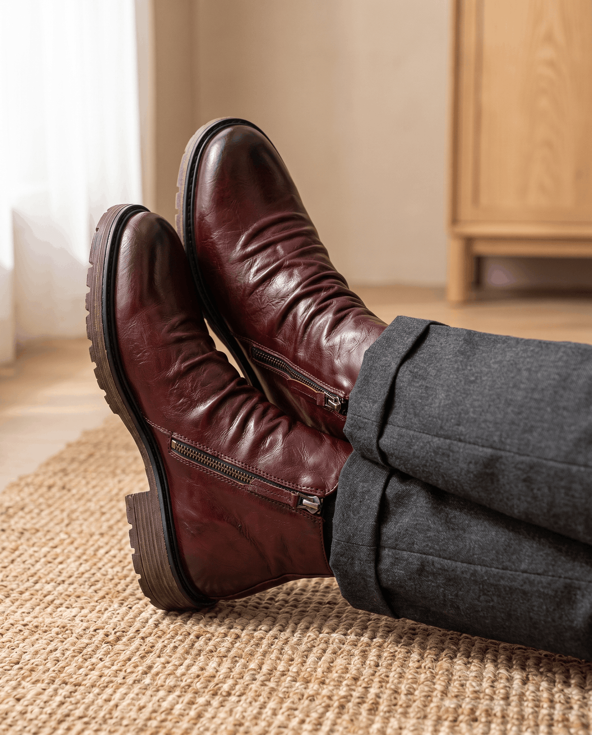 Deep red waxed leather boots with a ruched shaft, side zip closure, and a rugged, slip-resistant rubber outsole.