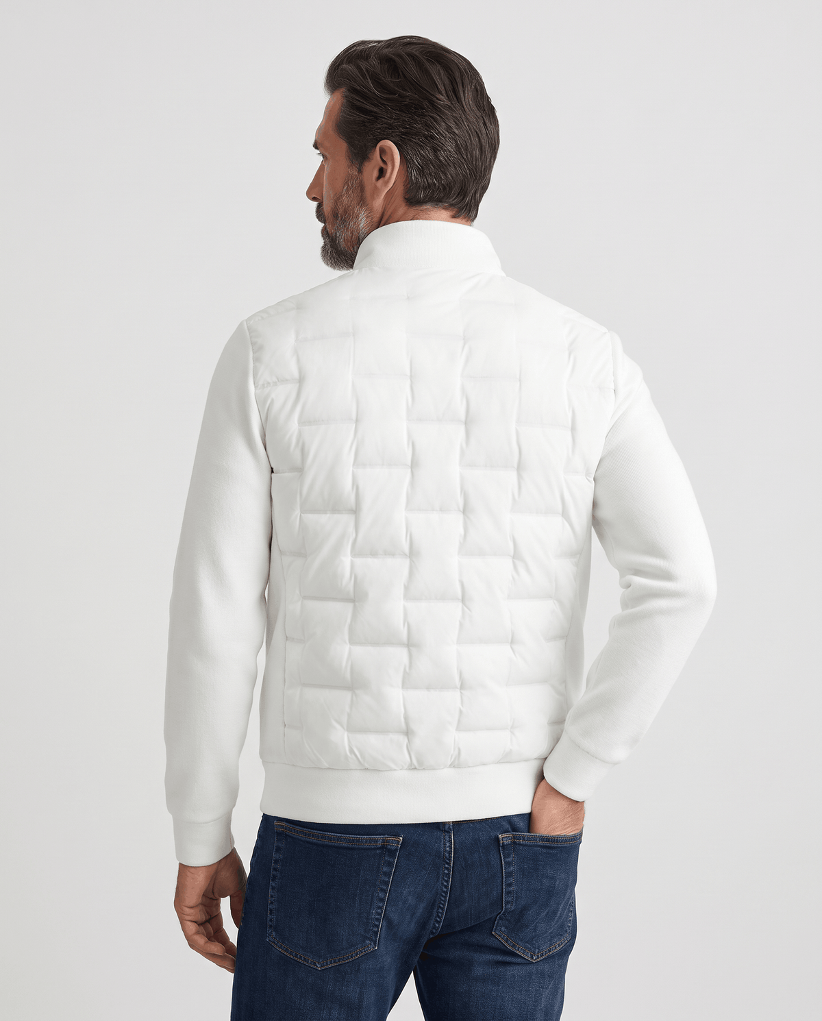 Back view of a man wearing a white quilted hybrid puffer jacket