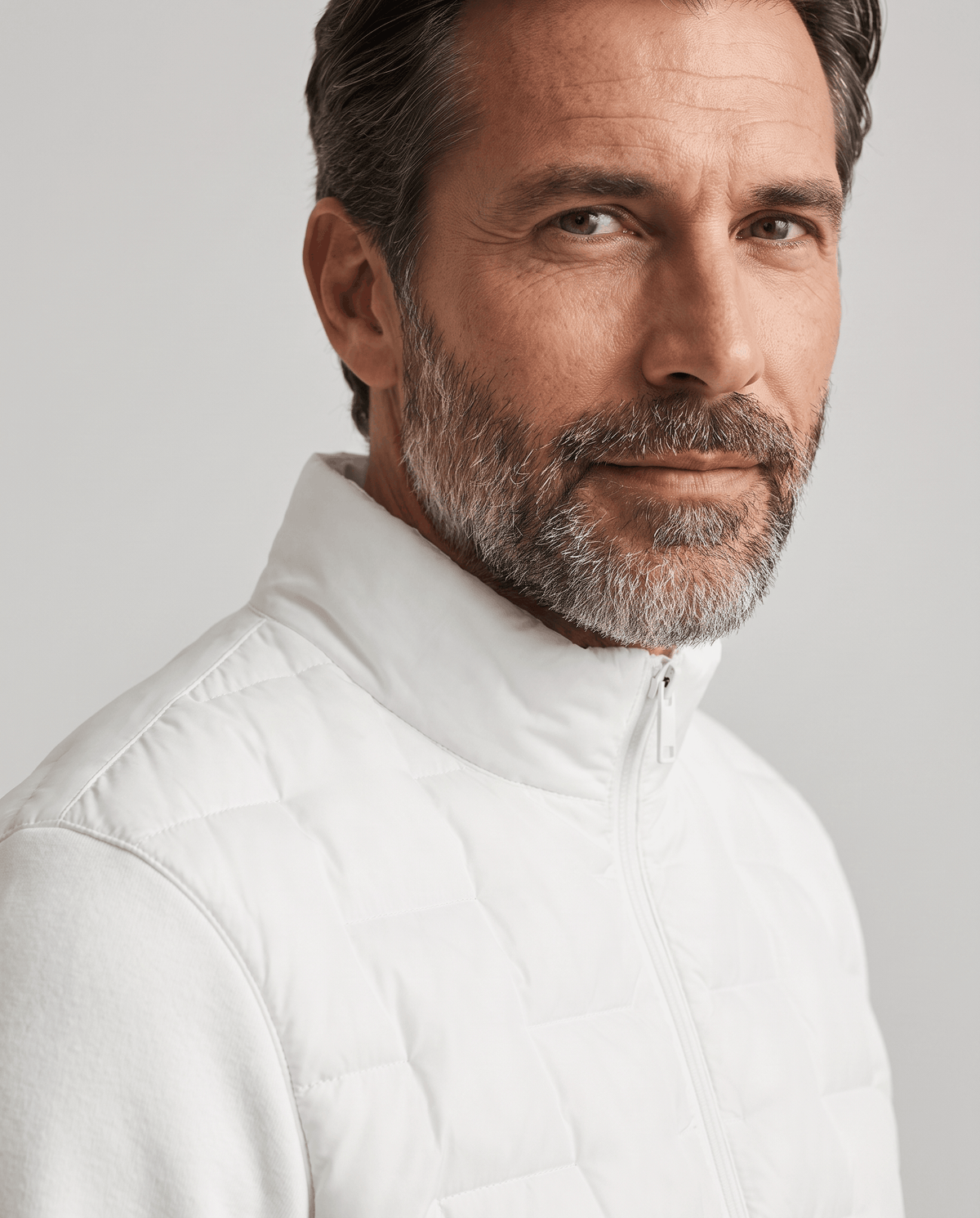 Close-up of the stand collar and quilted front on a white hybrid puffer jacket