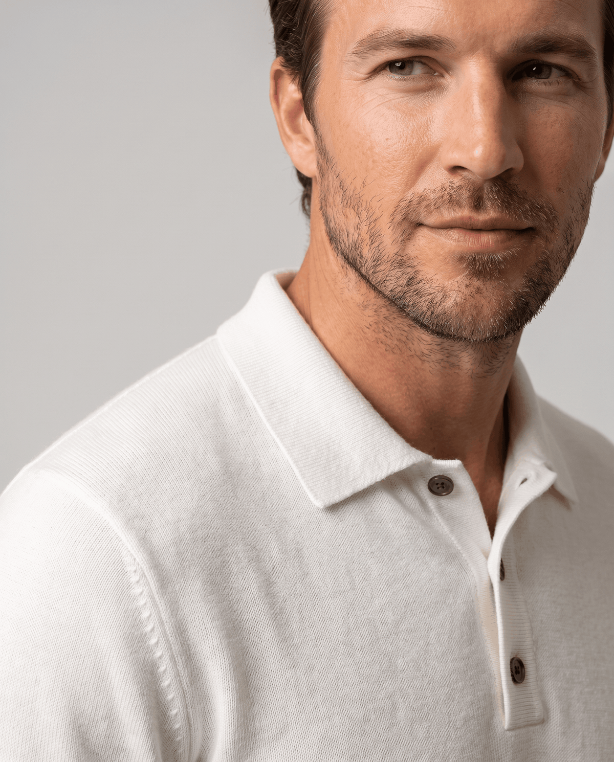 Close-up of the collar and button placket on the Elias white wool knit polo sweater
